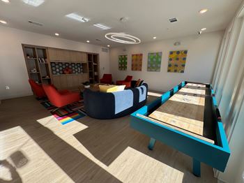 A room with a pool table and a shelf with books and a couch.